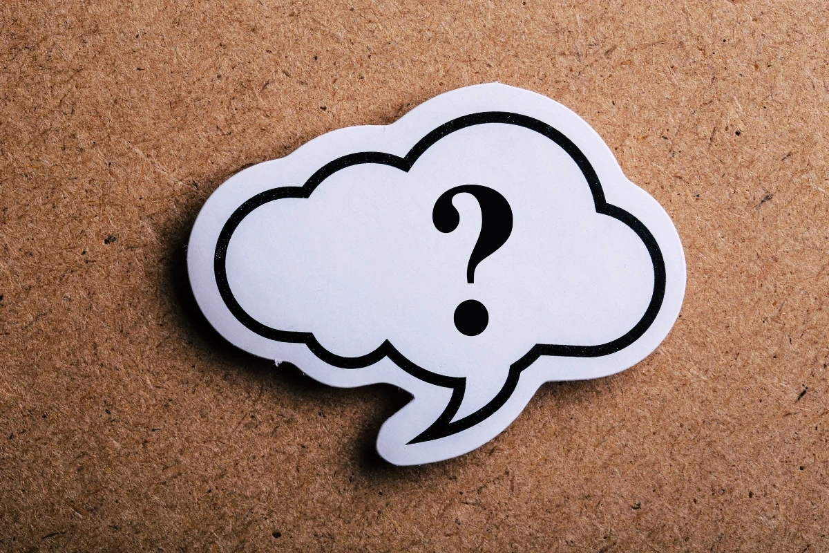 Biela bublina s čiernym tučným otáznikom na hnedom podklade.