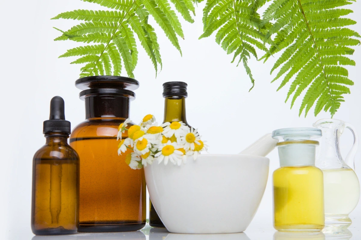 Sklenené fľaštičky, mažiar a harmanček ako symboly prírodných liečiv.