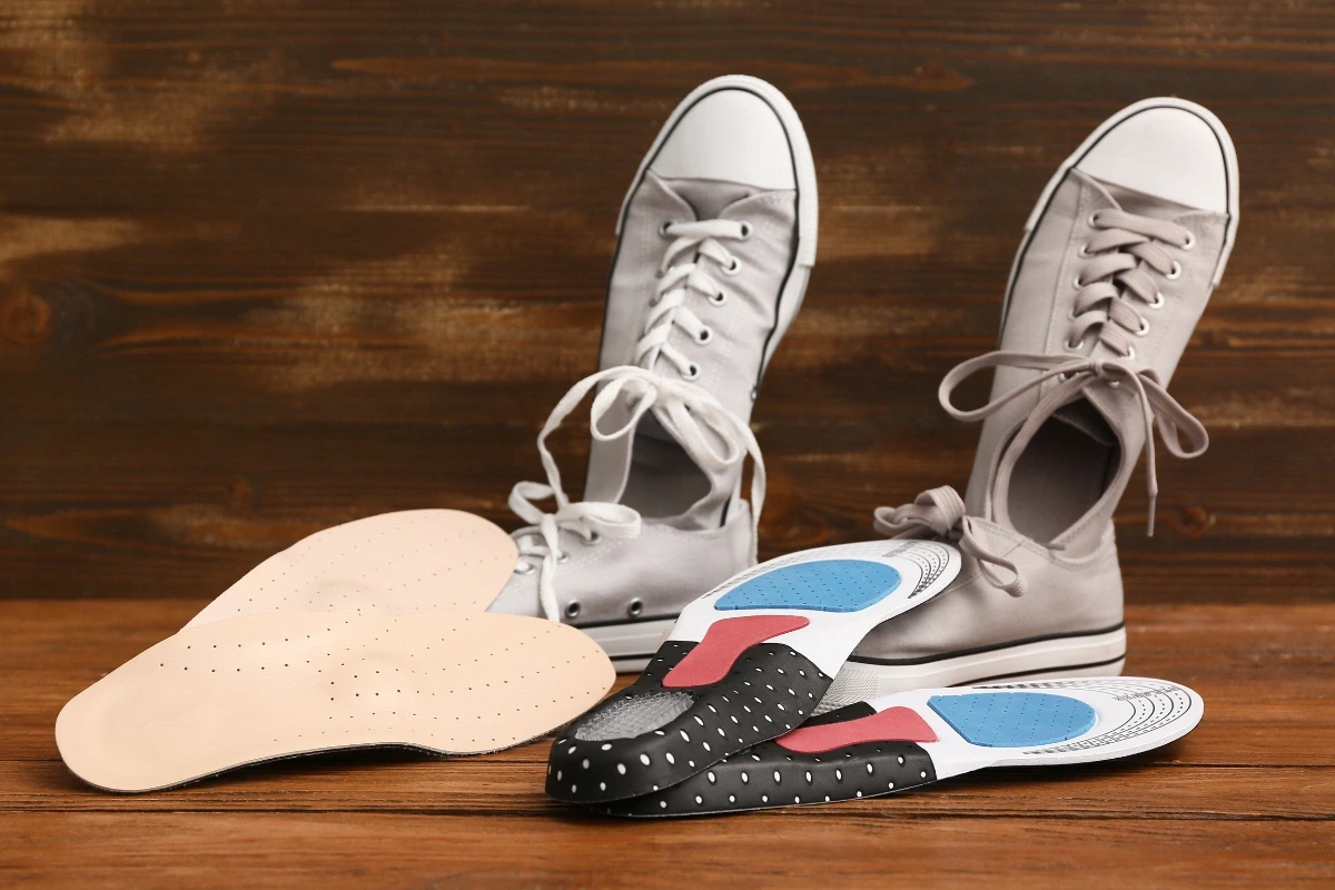 Dva páry šedých tenisiek, pri ktorých sú položené ortopedické vložky.