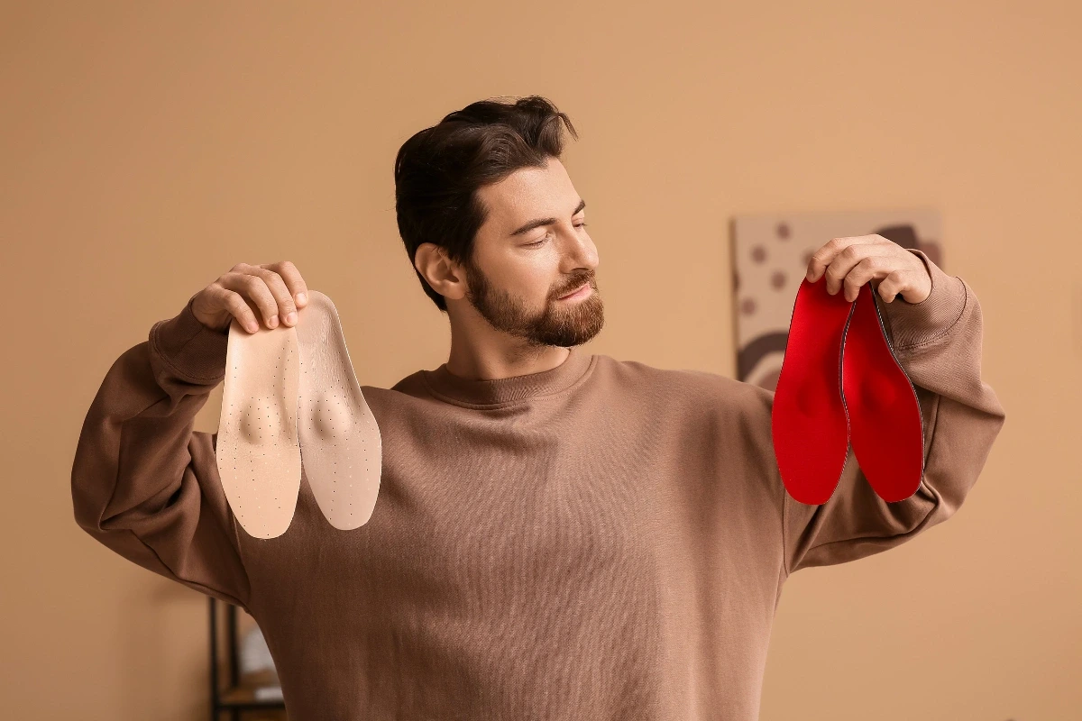 Muž drží v každej ruke jeden pár ortopedických vložiek.