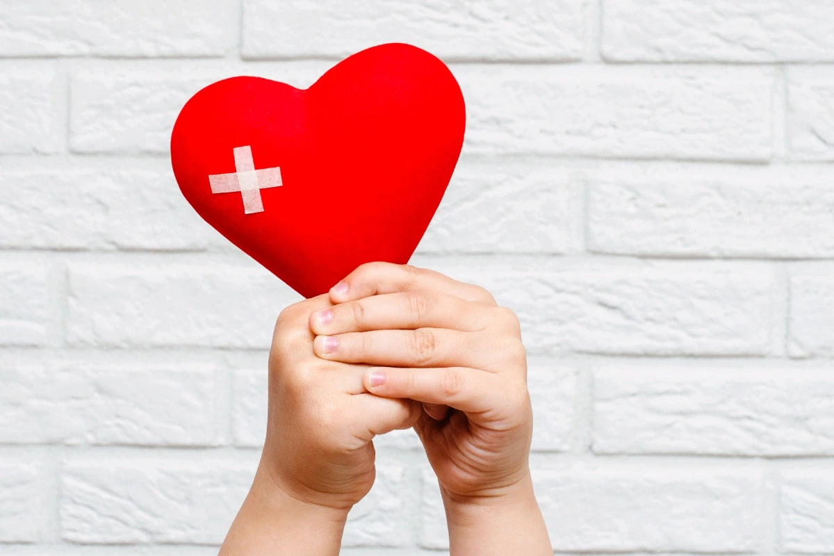  Detské ruky držia srdce so záplatou – symbol pomoci a podpory Zdravého Nákupu.