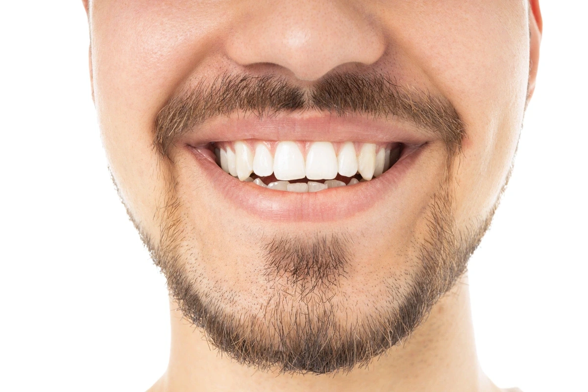 Detailný záber na mužský úsmev s bielymi a zdravými zubami.
